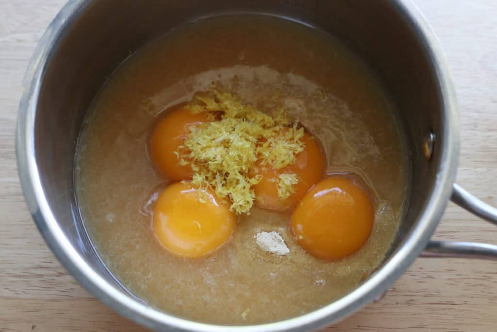 eggs and lemon zest and juice in a pot to make lemon curd for freshly milled lemon poppyseed rolls