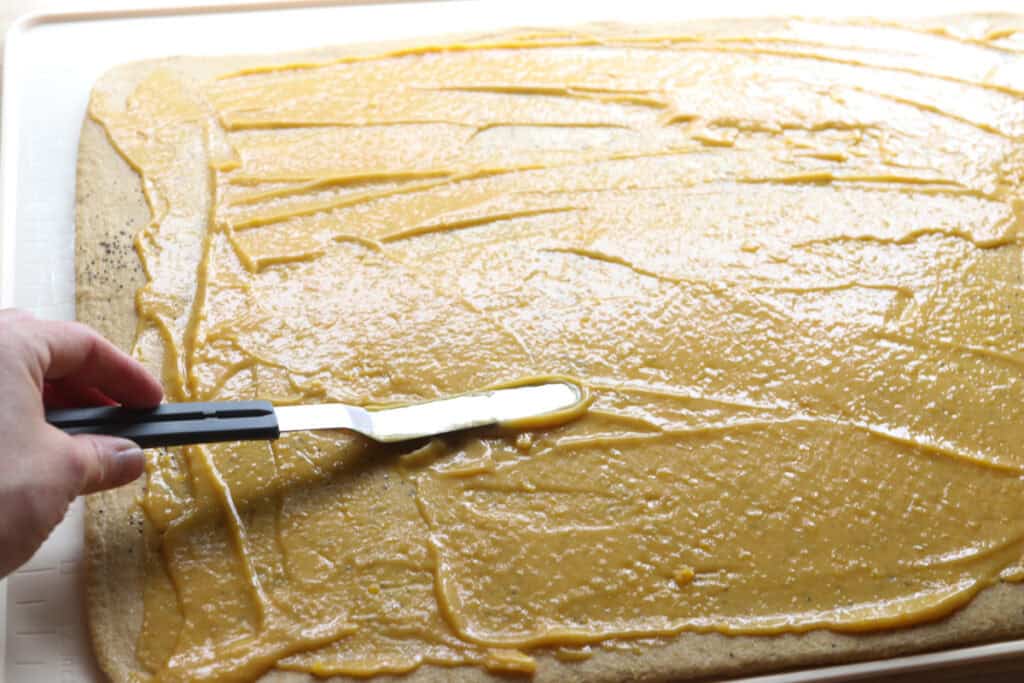 spreading lemon curd over the freshly milled lemon poppy seed dough