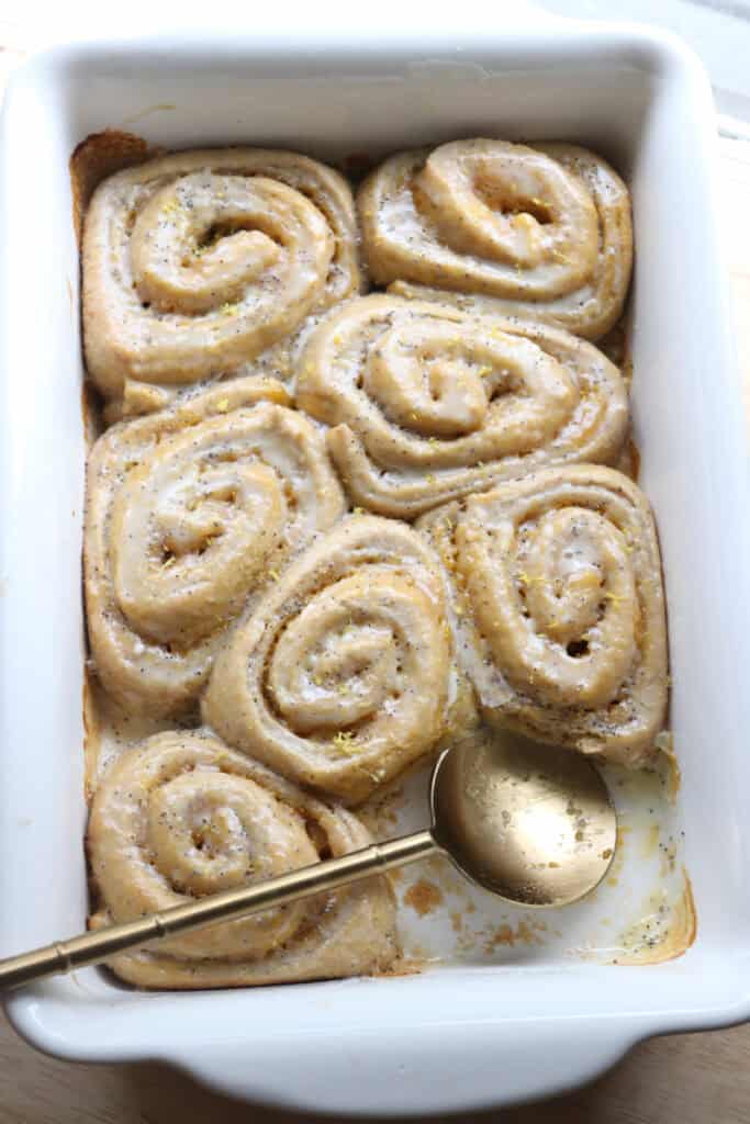 freshly milled lemon poppy seed rolls in a white dish with a gold spoon