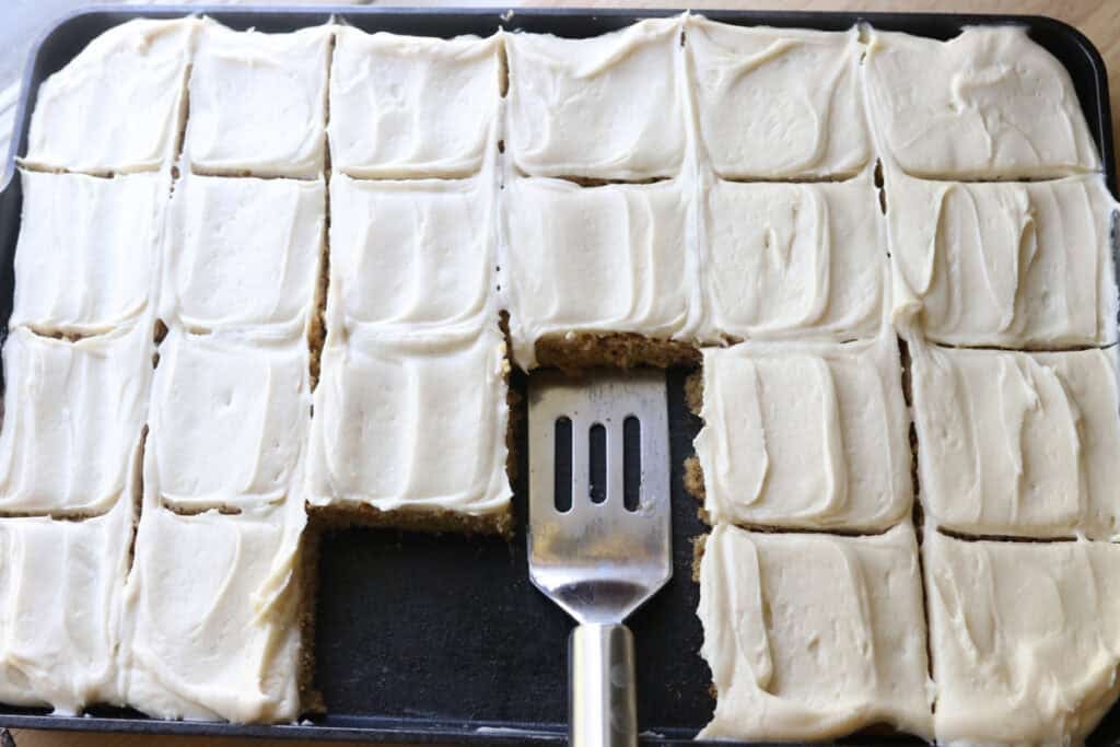 freshly milled frosted banana bars cut into bars with a spatula in it