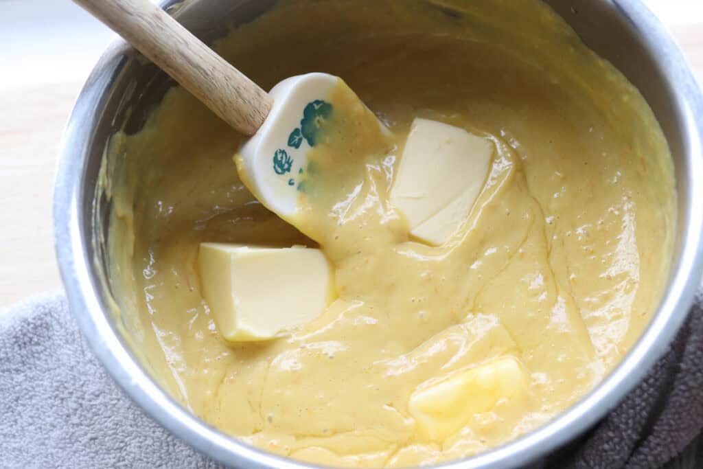 stirring butter into the orange curd for the Freshly milled orange almond poppy seed cake
