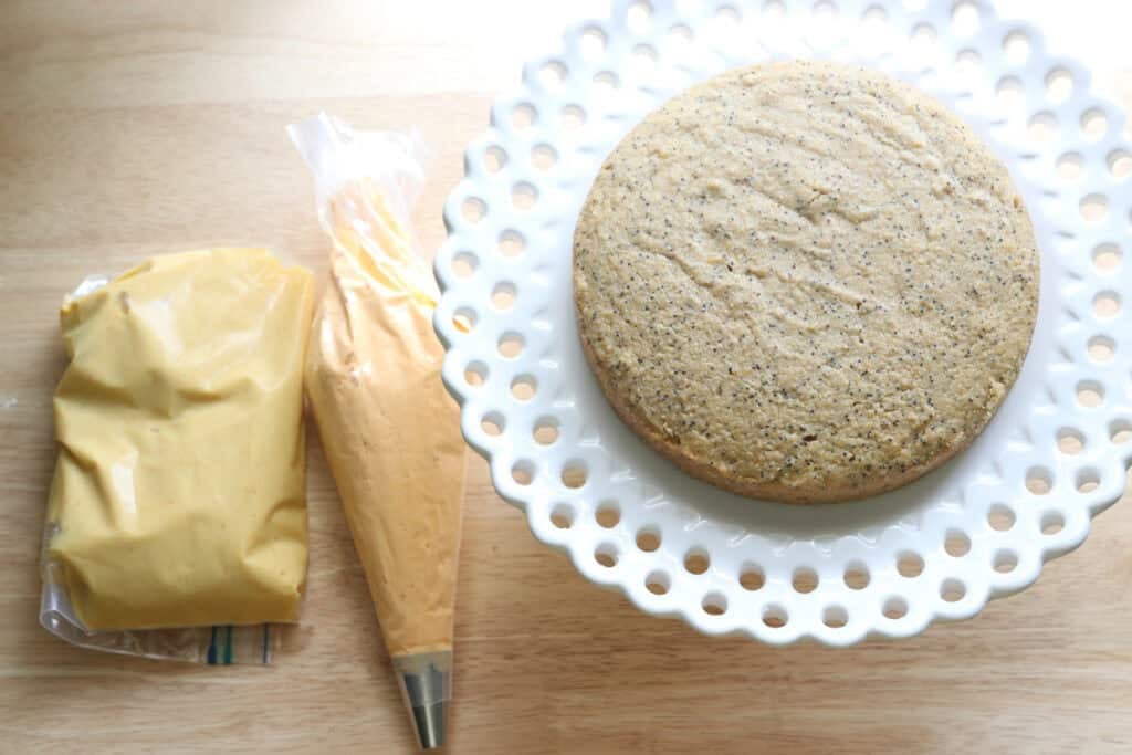 a layer of a Freshly milled orange almond poppy seed cake with a bag of icing and lemon curd