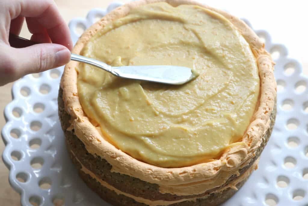 spreading lemon curd onto the Freshly milled orange almond poppy seed cake