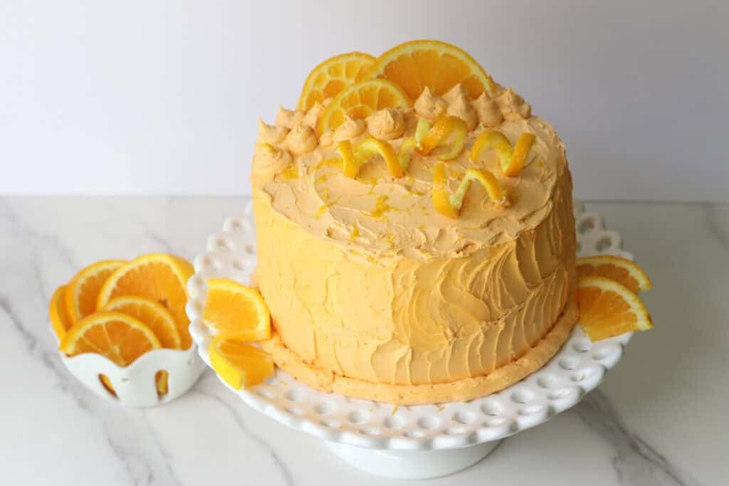 Freshly milled orange almond poppy seed cake on a white cake stand