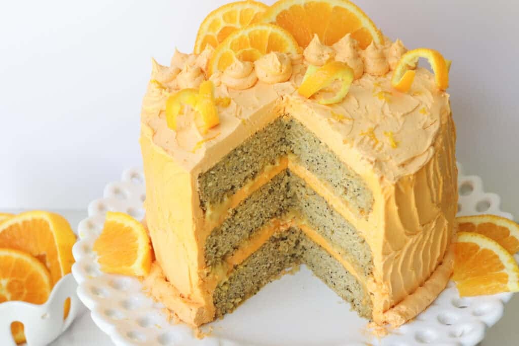 Freshly milled orange almond poppy seed cake with a slice cut out and buttercream between the layers