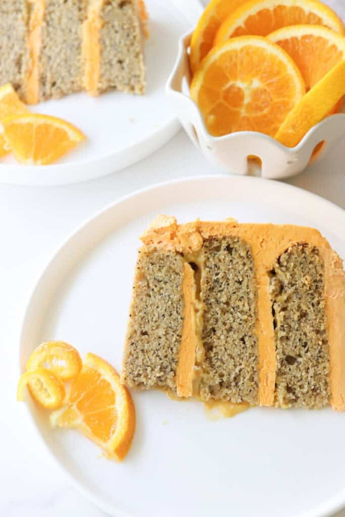 a slice of Freshly milled orange almond poppy seed cake on a plate with an orange slice