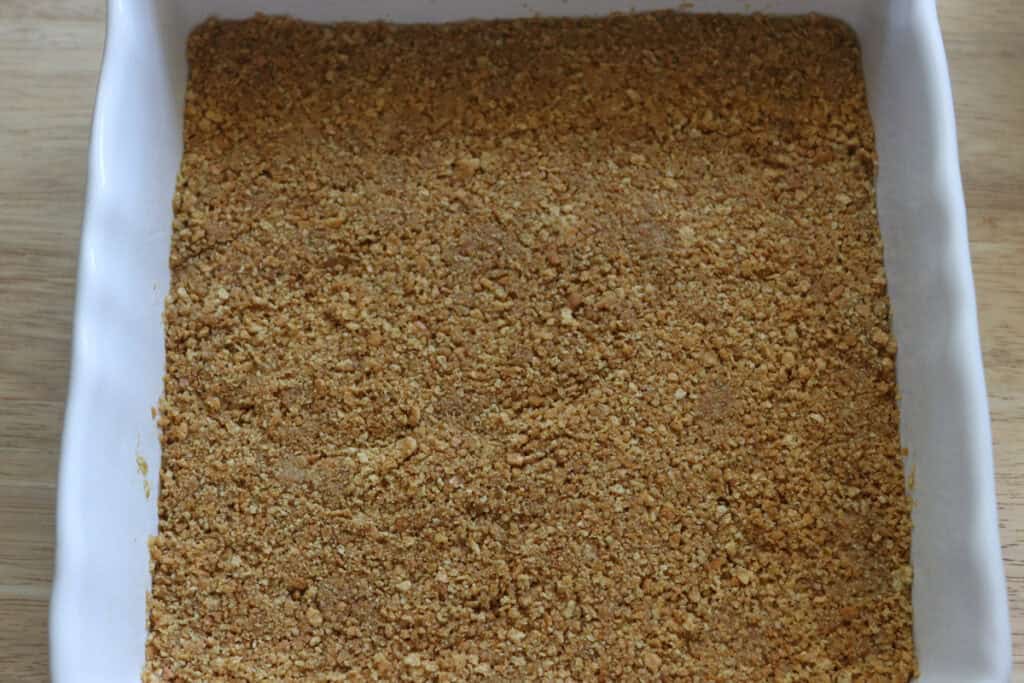 freshly milled graham crackers pressed into a pan to make freshly milled mango cheesecake bars