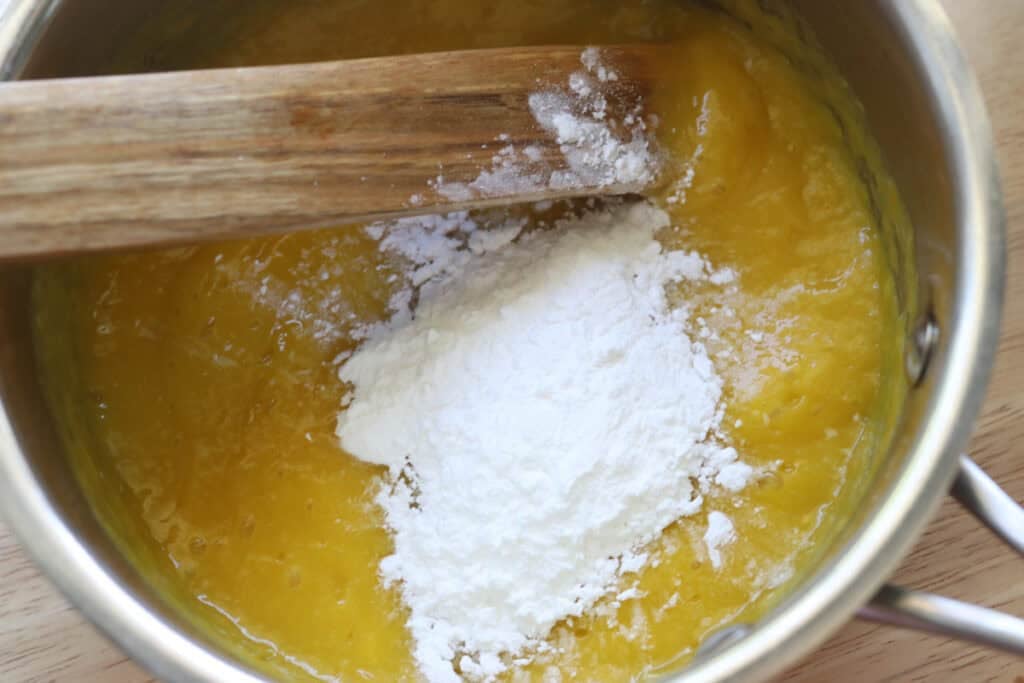 pureed frozen mangos in a pot to make freshly milled mango cheesecake bars
