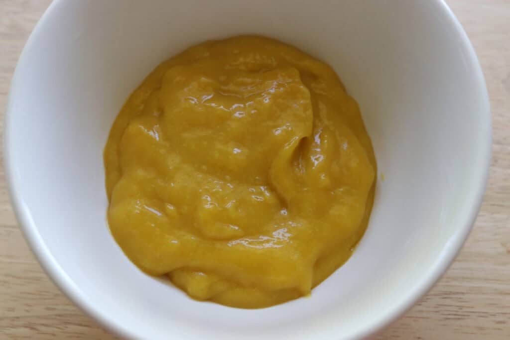 mango puree in a white bowl to make freshly milled mango cheesecake bars