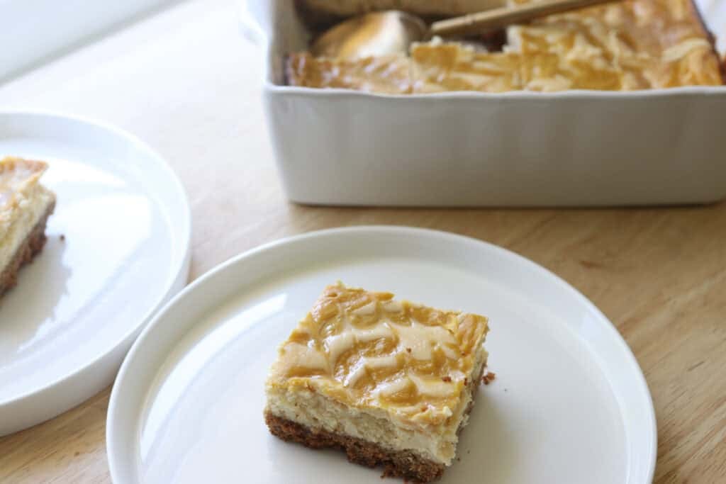 a freshly milled mango cheesecake bar on a white plate