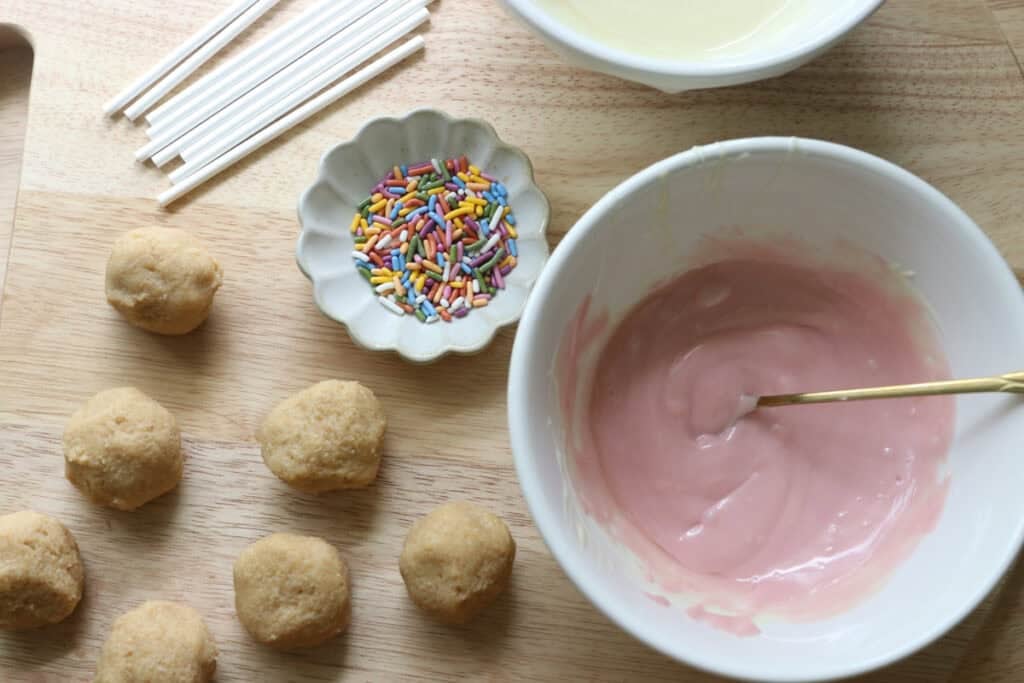 chocolate melted in a bowl with Freshly milled cake pops and sprinkles