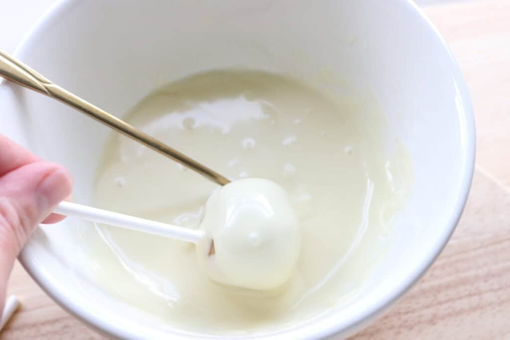 rolling a Freshly milled cake pop in white chocolate