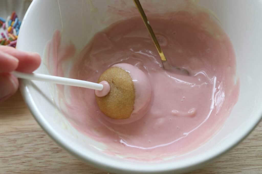 rolling a Freshly milled cake pop in pink white chocolate