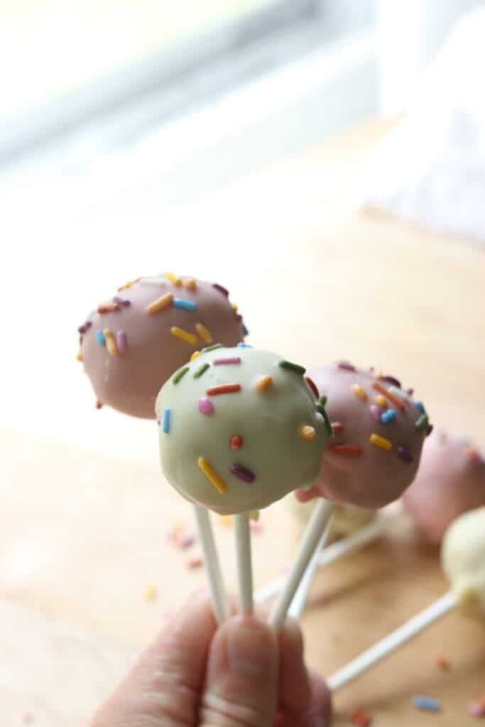 someone holding three Freshly milled cake pops