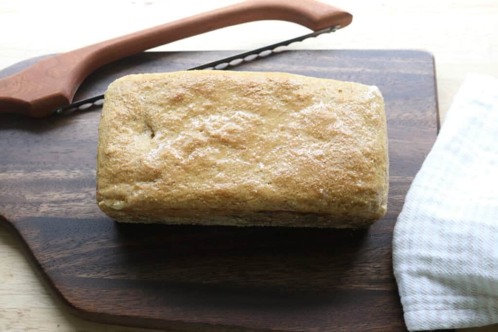 A loaf of freshly milled english muffin toasting bread on a cutting board with a knife
