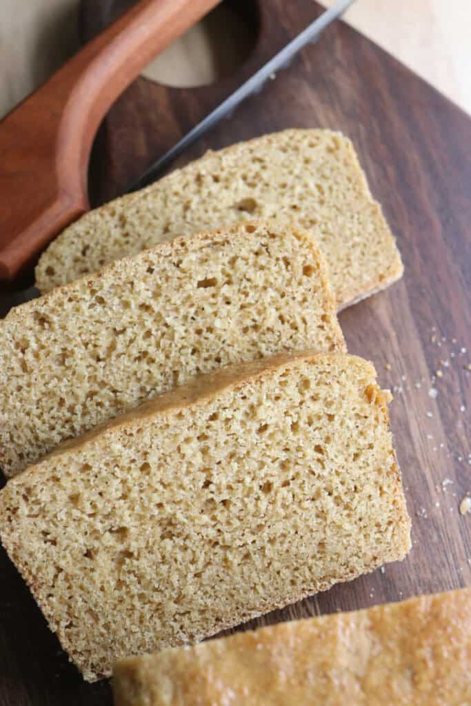 3 slices of freshly milled english muffin toasting bread on a wooden cutting board with a knife