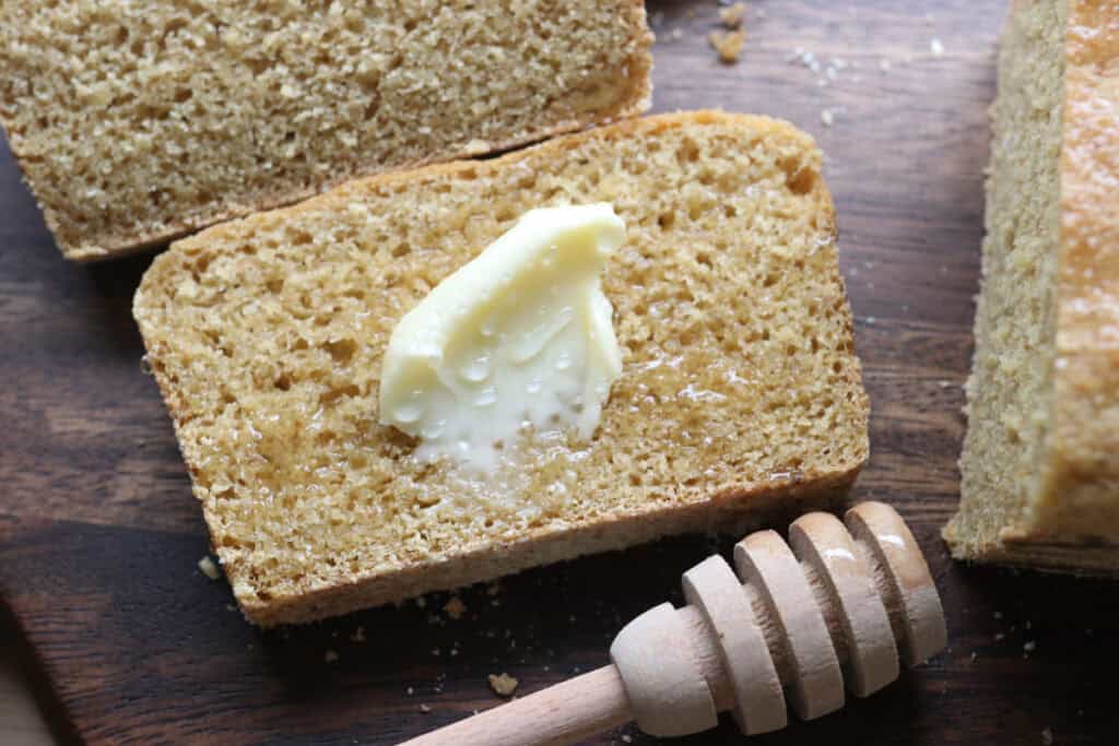 a slice of freshly milled english muffin toasting bread with butter and honey on it