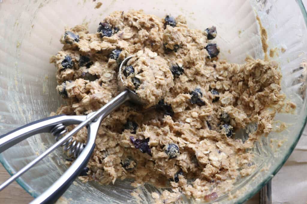 freshly milled blueberry cheesecake oatmeal cream pie batter in a bowl with a cookie scoop