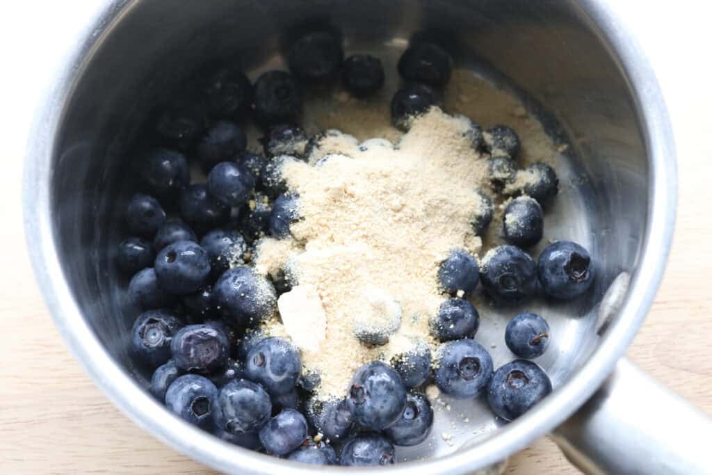 blueberries and sugar in a saucepan to make the jam for freshly milled blueberry cheesecake oatmeal cream pies