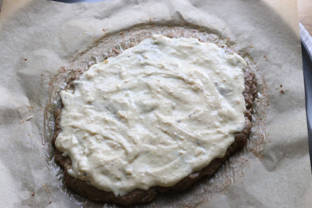 chicken crust baked on a pizza pan and topped with alfredo sauce to make high protein chicken crust chicken alfredo pizza