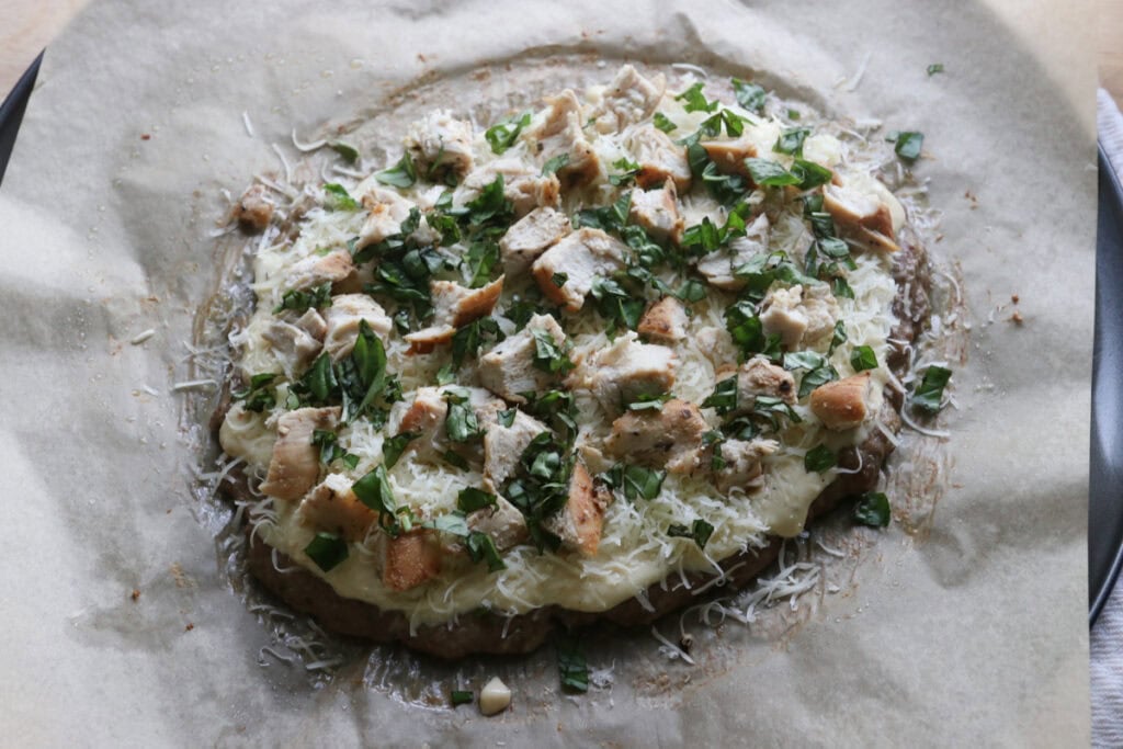 high protein chicken crust chicken alfredo pizza topped with mozzarella and fresh basil and chicken breast