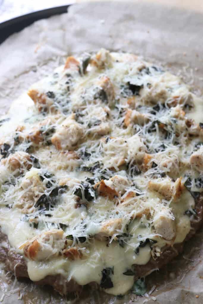 high protein chicken crust chicken alfredo pizza topped with parmesan and baked in the oven