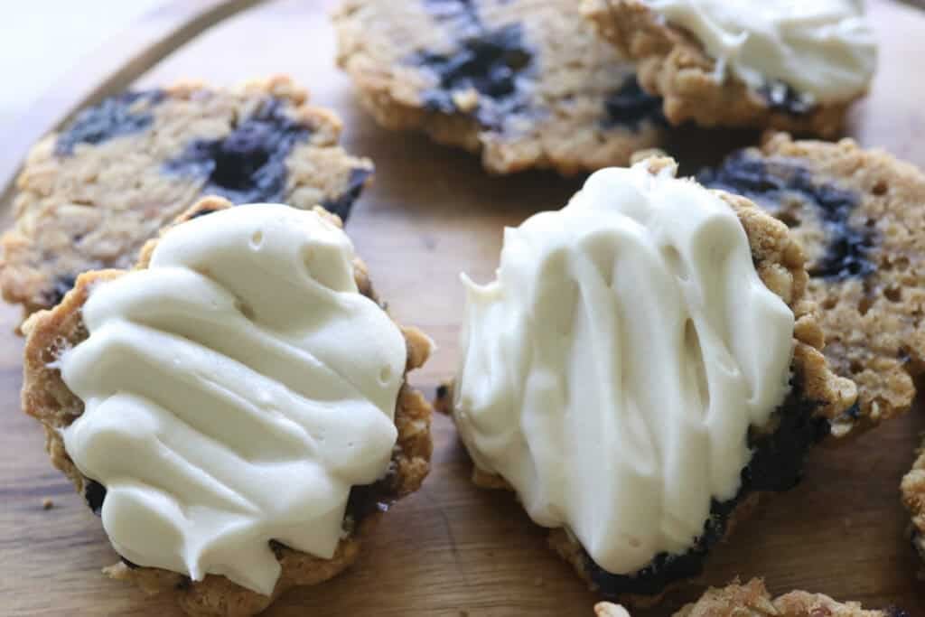 freshly milled blueberry cheesecake oatmeal cream pie cookies that have been iced
