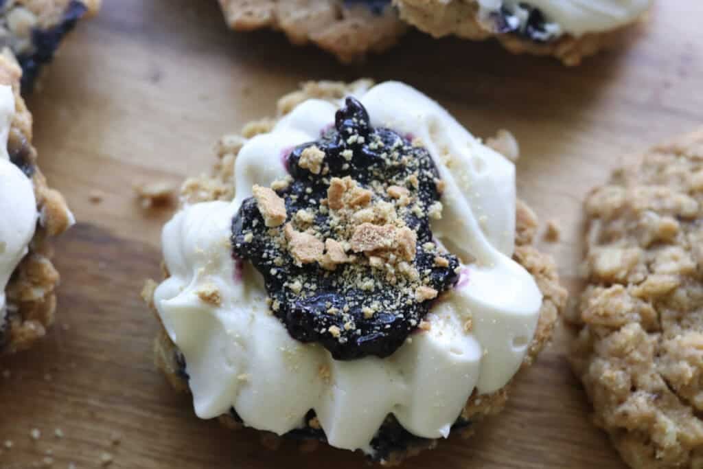half of a freshly milled blueberry cheesecake oatmeal cream pie with jam and crushed graham crackers on it