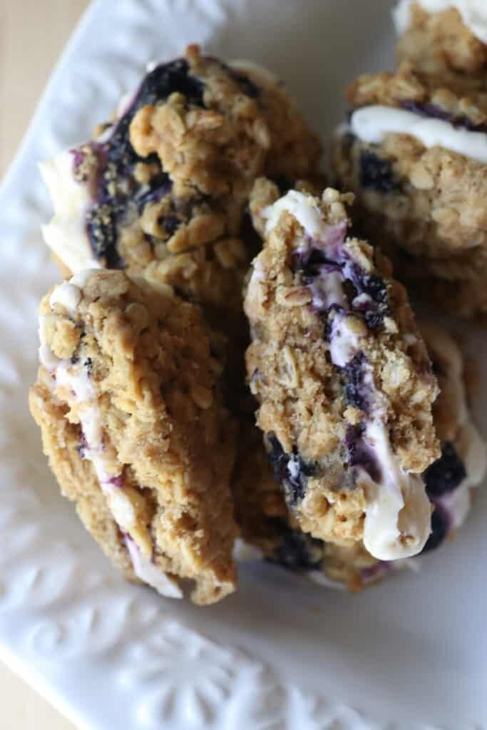 freshly milled blueberry cheesecake oatmeal cream pies cut in half with icing and blueberries inside