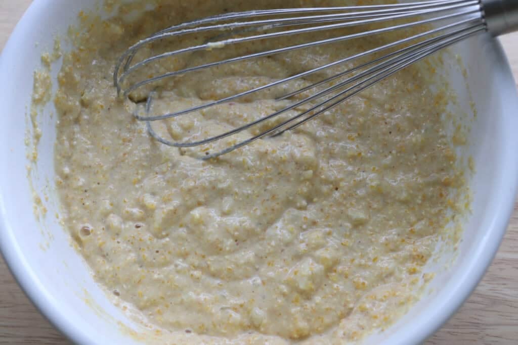 Freshly milled hush puppy batter in a bowl with a whisk
