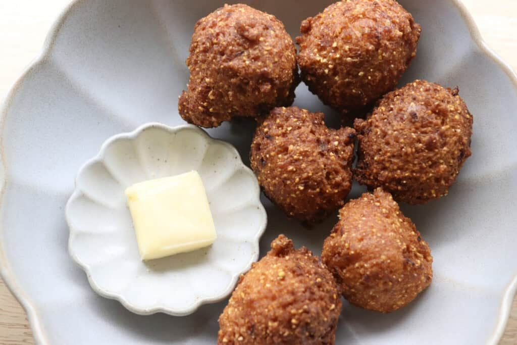 Fried hush puppies in a bowl with a slice of butter
